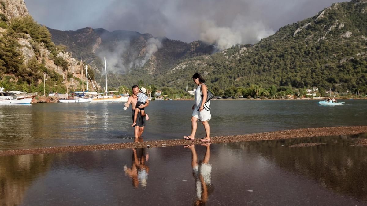 Tourists walk along a beach during a wildfire near Marmaris, Turkey. Credit: Reuters Photo
