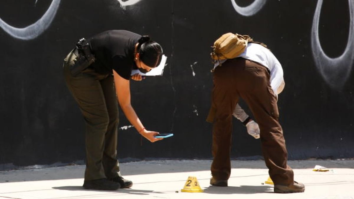 Forensic technicians work at a crime scene where unknown assailants murdered two people, in Ciudad Juarez. Credit: Reuters Photo