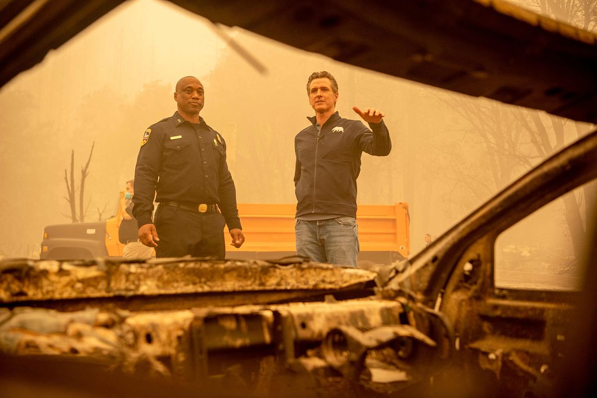 California Governor Gavin Newsom (R) looks at a burned vehicle alongside Assistant Region Chief for Cal Fire Curtis Brown (L) in downtown Greenville, California. Credit: AFP Photo