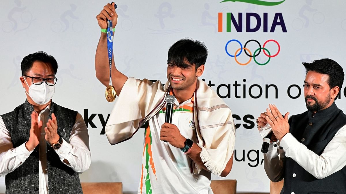 Neeraj Chopra poses with his gold medal as Sports Minister Anurag Thakur and Law & Justice Minister Kiren Rijiju look on. Credit: AFP Photo