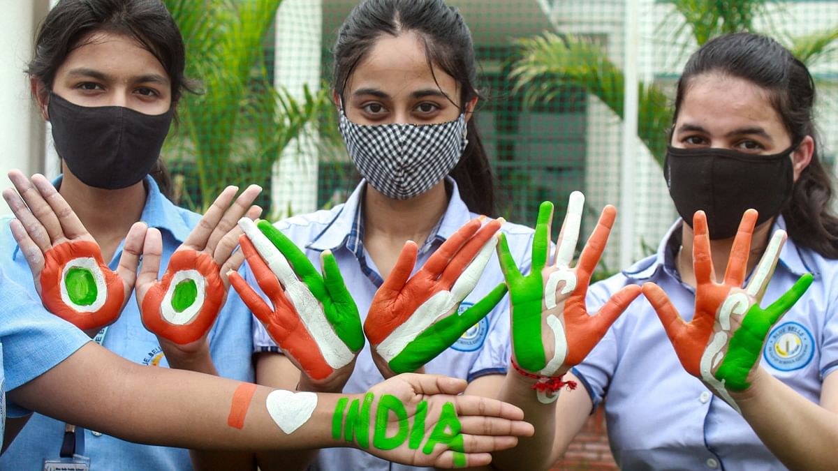 Students with their hand painted in tricolour pose for photographs during rehearsal, ahead of the 75th Independence Day function in Gurugram. Credit: PTI Photo