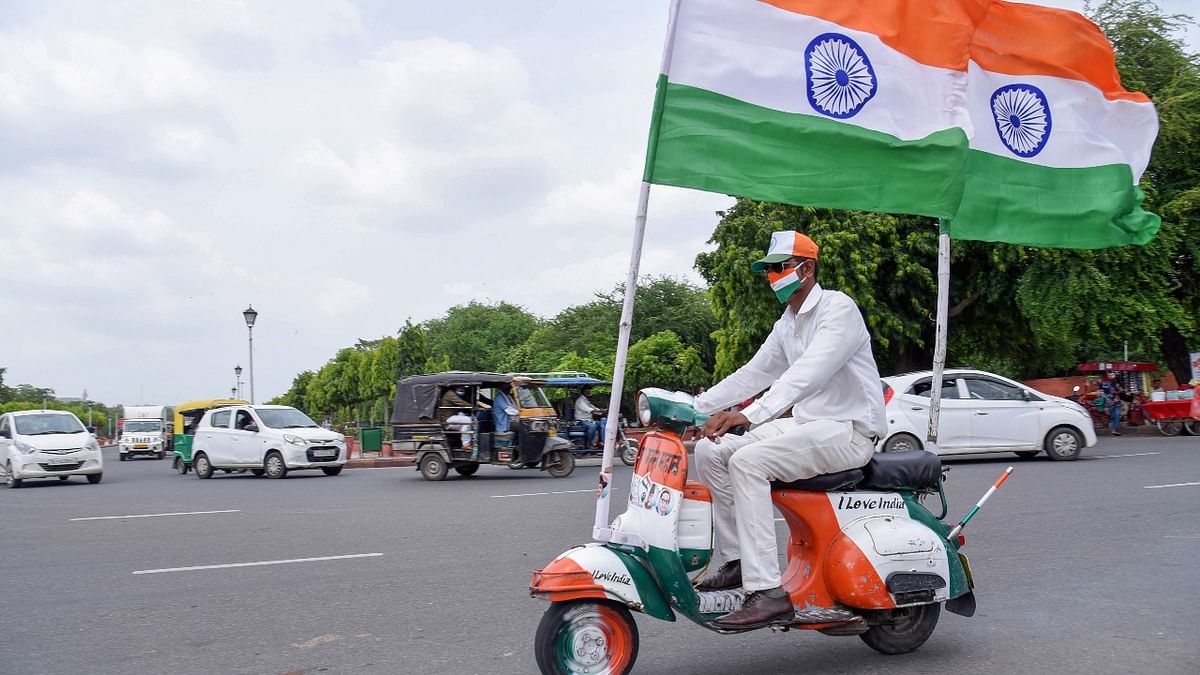 A man rides a scooter painted in the tri-colour and two huge flags fixed on it, ahead of the Independence Day, in Jaipur. Credit: PTI Photo