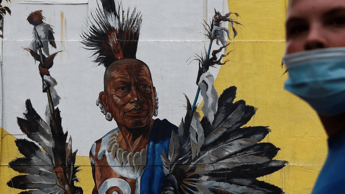 A man wearing a protective face mask amid the coronavirus disease pandemic walks by the Pepe Gaka Quapaw Mural in Hot Springs. Credit: Reuters Photo