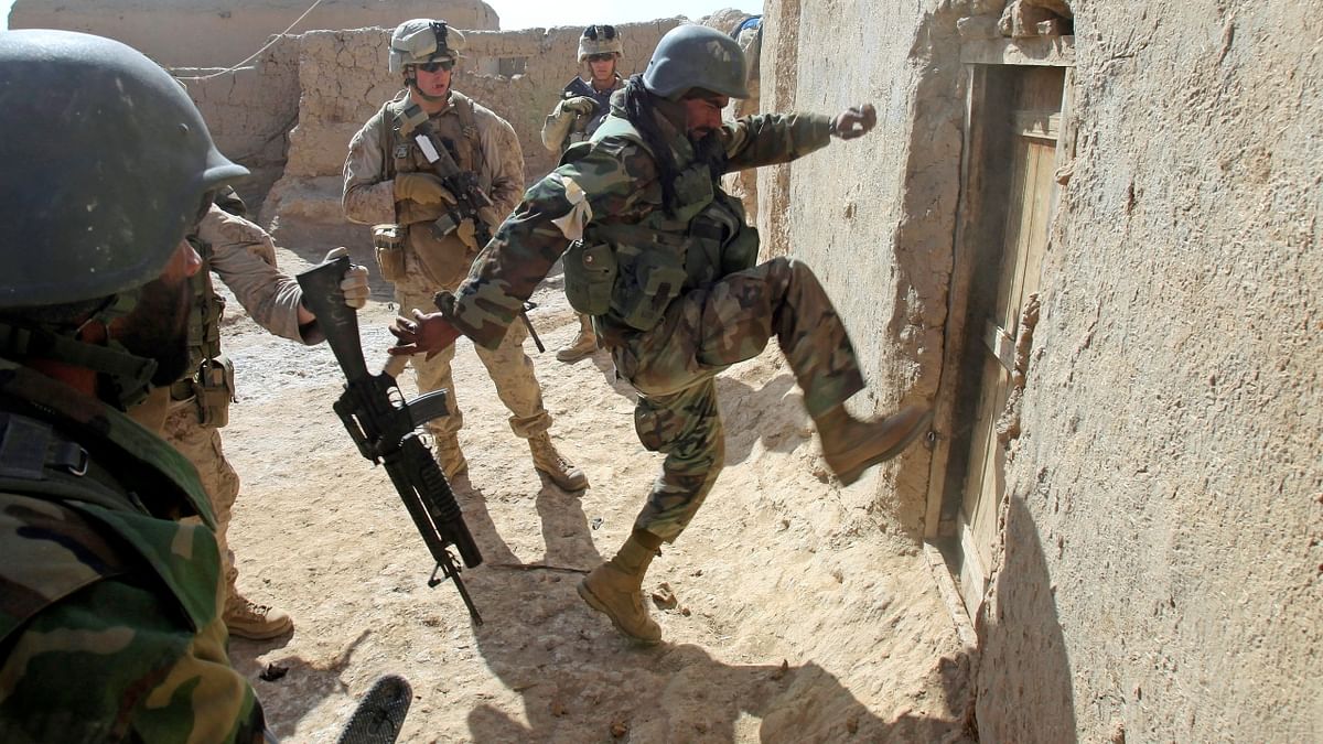 An Afghan soldier attempts to break open a door as US Marines from Bravo Company of the 1st Battalion, 6th Marines, look on during an operation to search for weapons in the town of Marjah, in Nad Ali district of Helmand province, Afghanistan. Credit: Reuters Photo