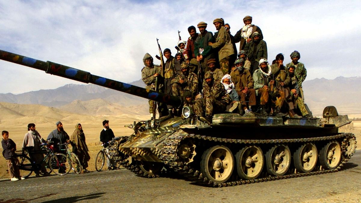 Northern Alliance fighters ride on a T-62 tank on the motorway 3km north of Kabul, as Northern Alliance fighters approached the Afghan capital on November 13, 2001. Credit: Reuters Photo