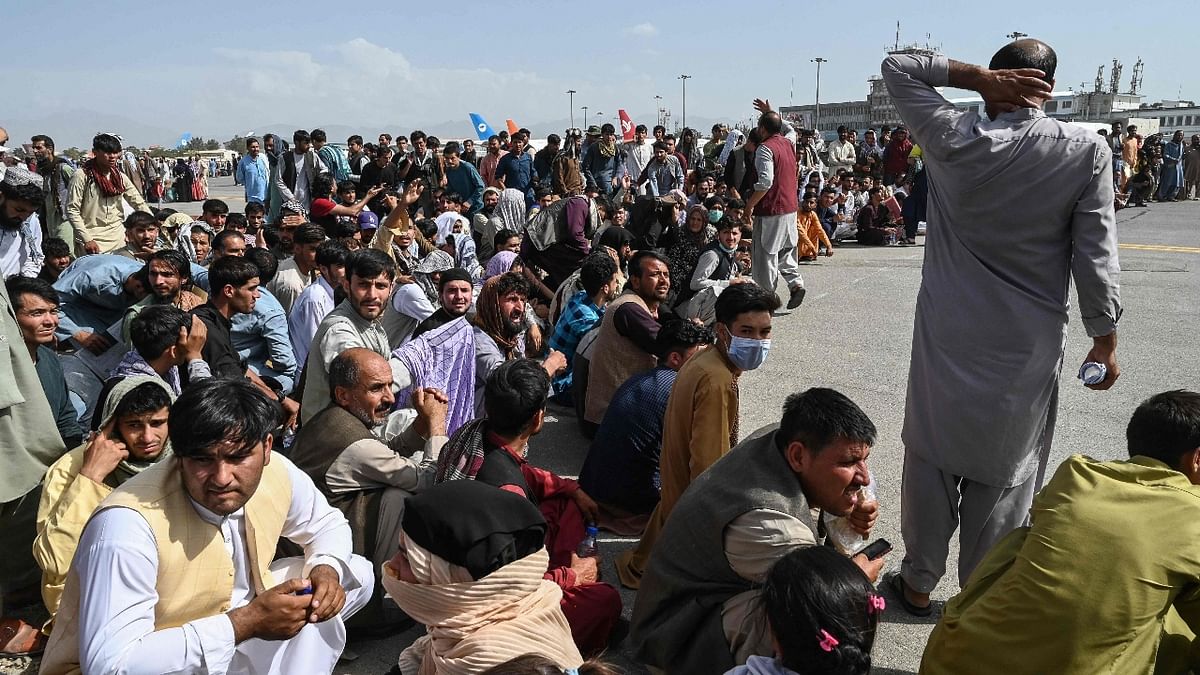 Afghan passengers sit as they wait to leave the Kabul airport after a stunningly swift end to Afghanistan's 20-year war. Credit: AFP Photo