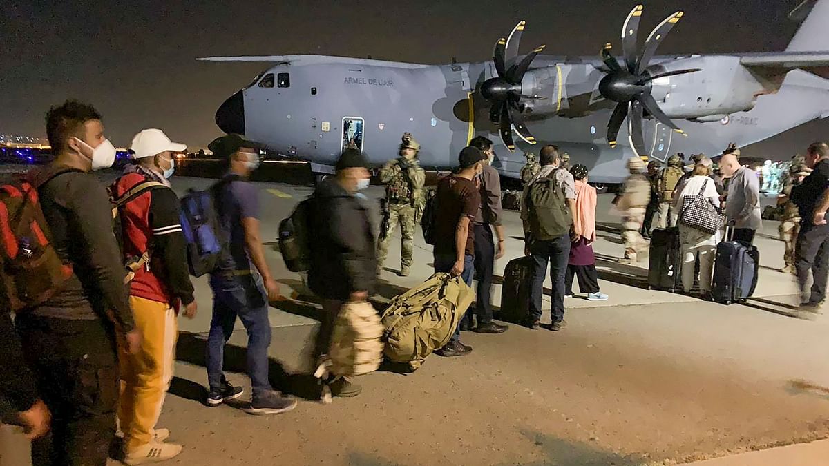 French nationals and their Afghan colleagues line up to board a French military transport plane at the Kabul airport on August 17, 2021. Credit: AFP Photo