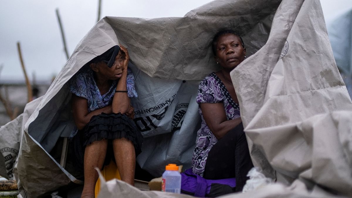 Two women shelter from the rain under a tarp in a makeshift camp after tropical depression Grace passed through the area following Saturday's 7.2 magnitude quake, in Les Cayes, Haiti. Credit: Reuters Photo
