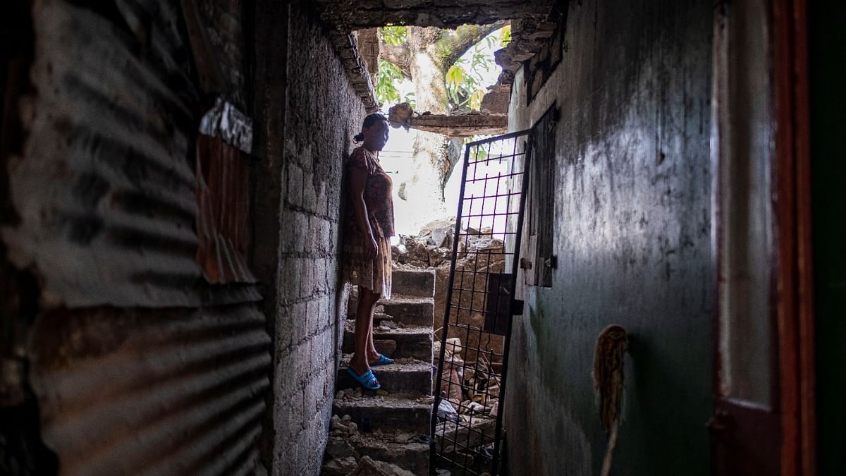 A woman stands inside her damaged house after Saturday's 7.2 magnitude quake, in Les Cayes, Haiti. Credit: Reuters Photo