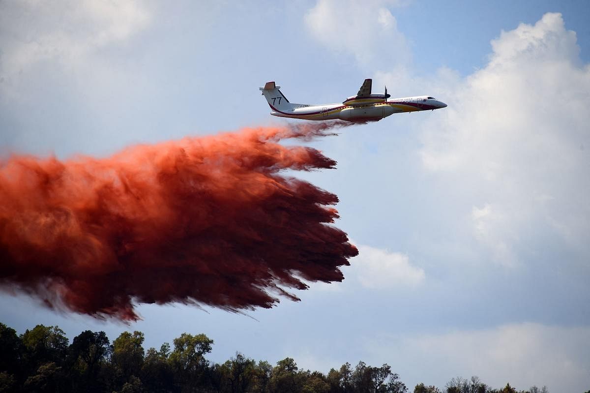 A Civil Security Bombardier Dash 8-Q400MR firefighting aircraft drops fire-retardant to avoid rework on small fireplaces due to wind, during wildfire in La Garde-Freinel in the department of Var, southern France. Credit: AFP Photo
