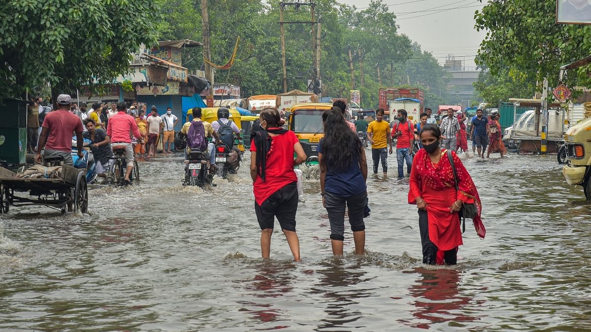 Commuters wade through a waterlogged street after rain at Jahangirpuri area in New Delhi. Credit: PTI Photo