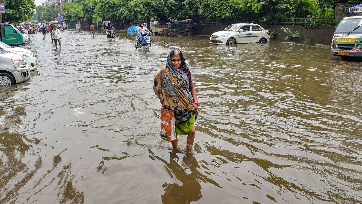A woman wades through a waterlogged street after rain at Jahangirpuri area in New Delhi. Credit: PTI Photo