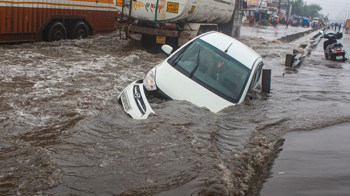 A car stuck on the waterlogged Delhi-Gurugram Expressway after heavy rain, at Narsinghpur in Gurugram. Credit: PTI Photo