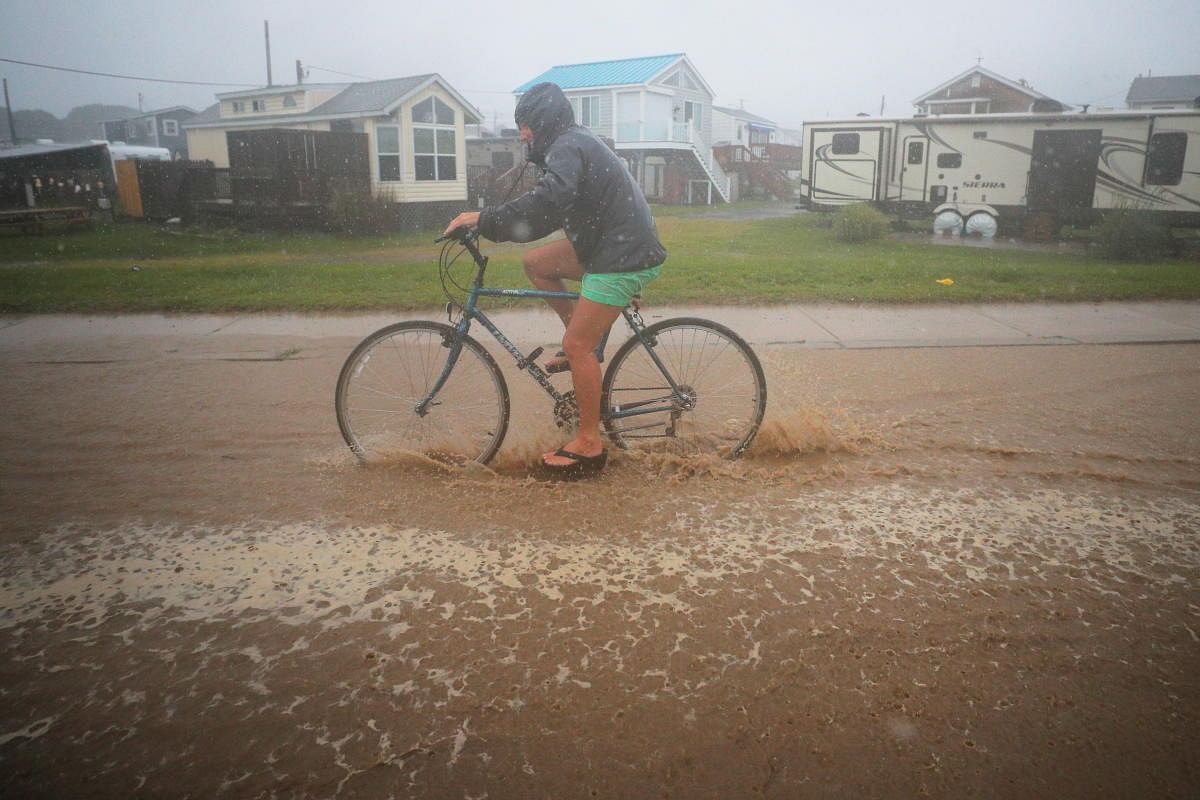 A bicyclist rides through a flooded street as Tropical Storm Henri approaches South Kingstown, Rhode Island, US. Credit: Reuters Photo