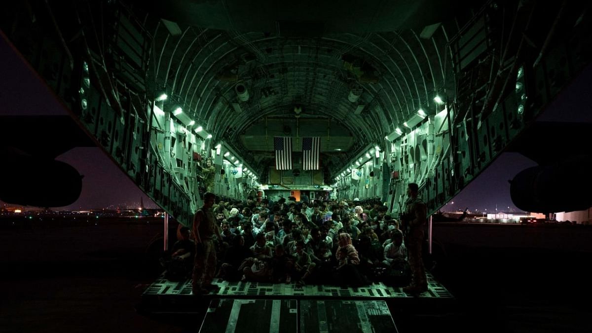 In this image courtesy of the US Air Force, a US Air Force aircrew, assigned to the 816th Expeditionary Airlift Squadron, assists qualified evacuees aboard a US Air Force C-17 Globemaster III aircraft in support of the Afghanistan evacuation at Hamid Karzai International Airport, Kabul, Afghanistan. Credit: AFP Photo