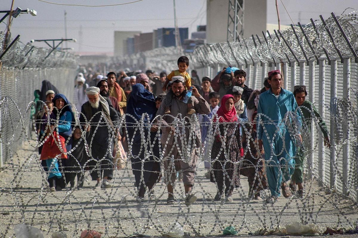 Afghans walk along fences as they arrive in Pakistan through the Pakistan-Afghanistan border crossing point in Chaman following Taliban's military takeover of Afghanistan. Credit: AFP Photo