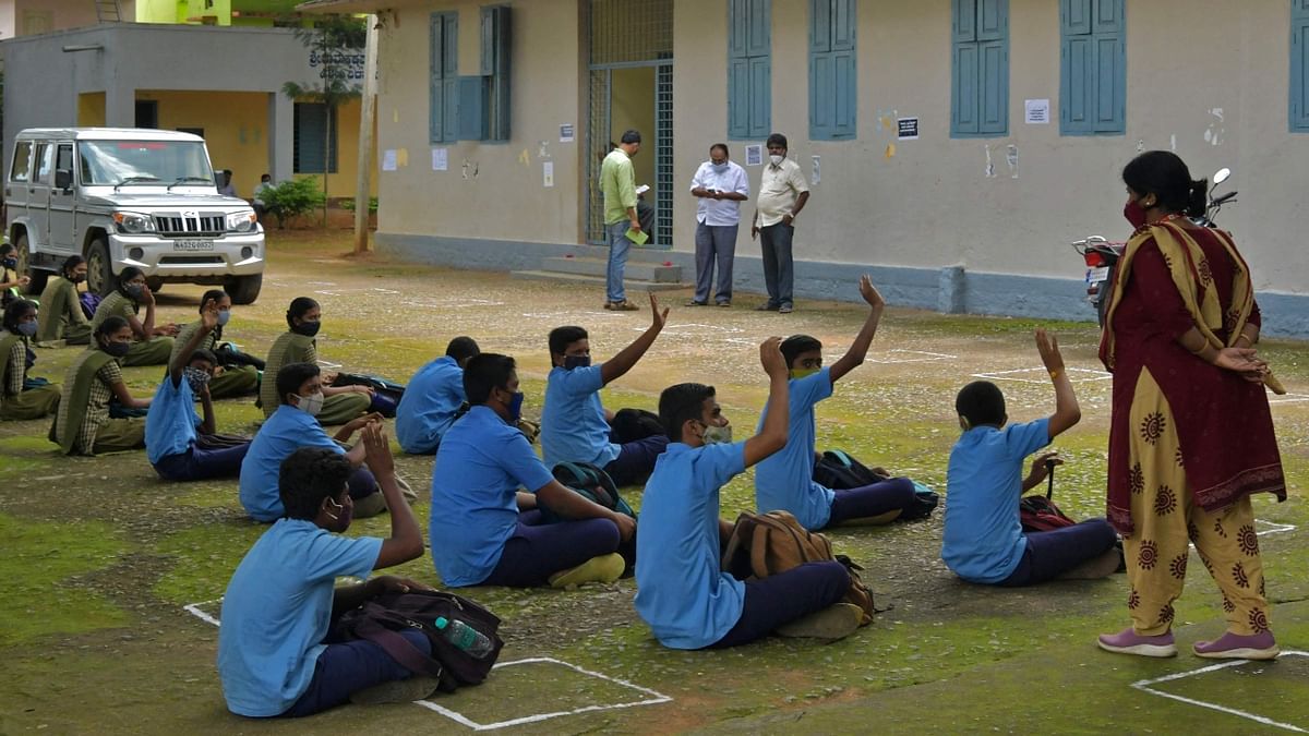 Students of a government school sit for a briefing about Covid-19 protocols on the first day of reopening of schools for the higher secondary classes with 50 percent capacity after 18 months of closure due to the coronavirus pandemic in Bengaluru. Credit: AFP Photo