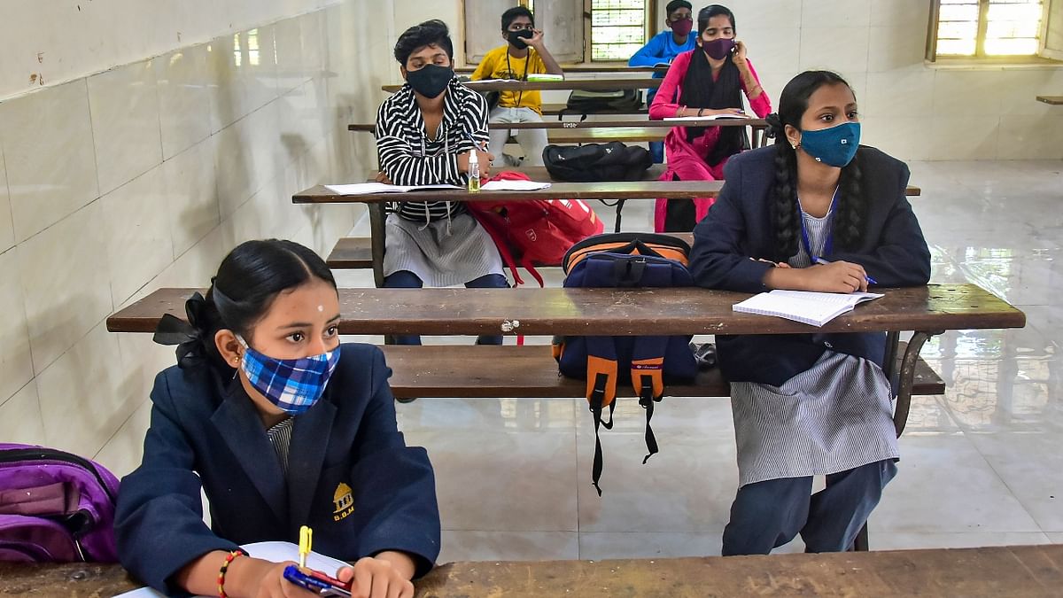 Students follow Covid-19 safety protocols as they attend a class after the Karnataka Government re-opened schools to conduct classes for 9th,10th and PUC in Bengaluru. Credit: PTI Photo