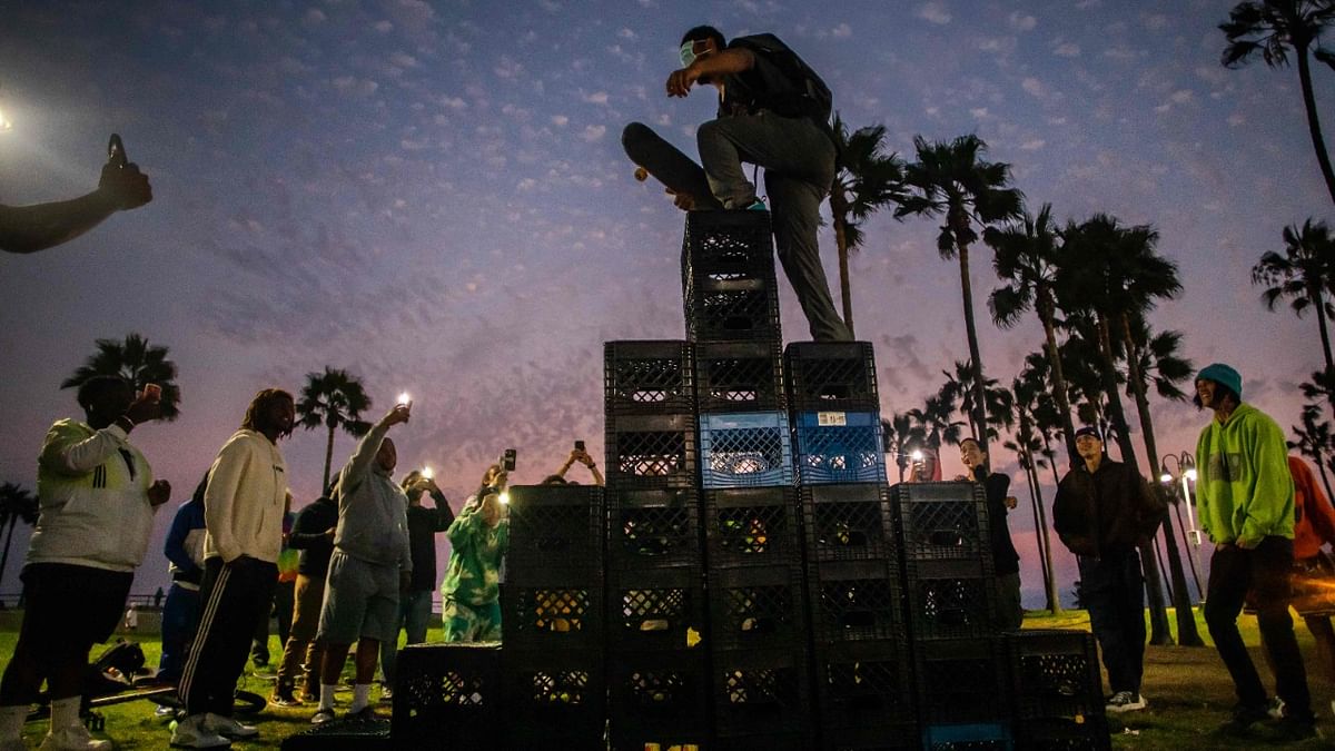 A man walks up a pyramid of milk crates while he participates of the Milk Crate Challenge, on August 24, 2021 in Venice, California. - The Milk Crate Challenge, where participants walk up a pyramid of milk crates has gone viral in recent days on social media. Credit: AFP Photo