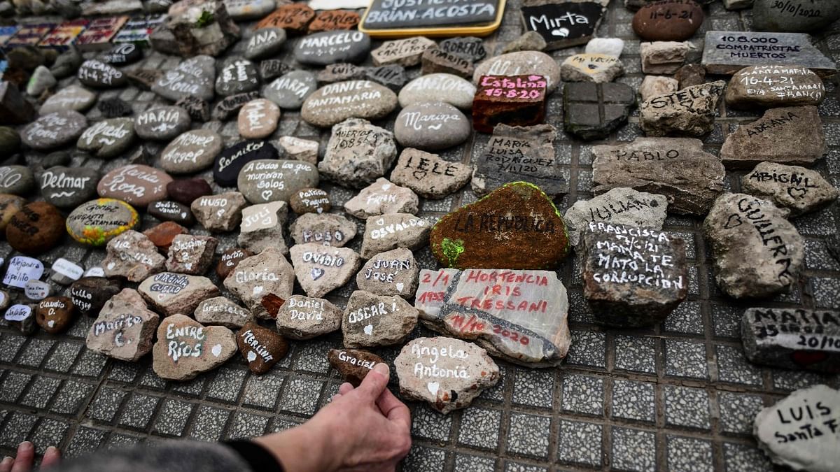 A woman places a stone with the name of a relative outside the Casa Rosada government house during the “march of the stones” in homage to Covid-19 victims, in Buenos Aires. Credit: AFP Photo