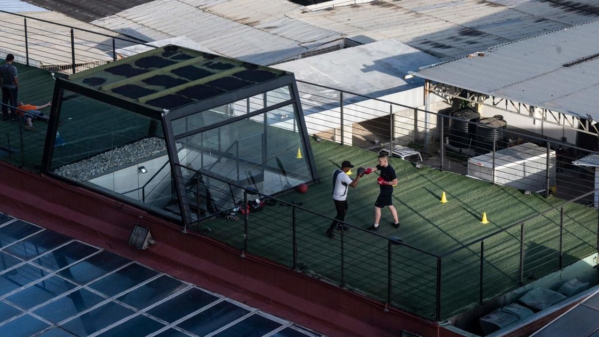 A youngster is trained by his boxing coach on the roof of a gym during a “radical week” -in which all business, except the first necessity ones, close- imposed by the government as part of a program to prevent the spread of the Covid-19 virus in Caracas on August 27, 2021. Credit: AFP Photo