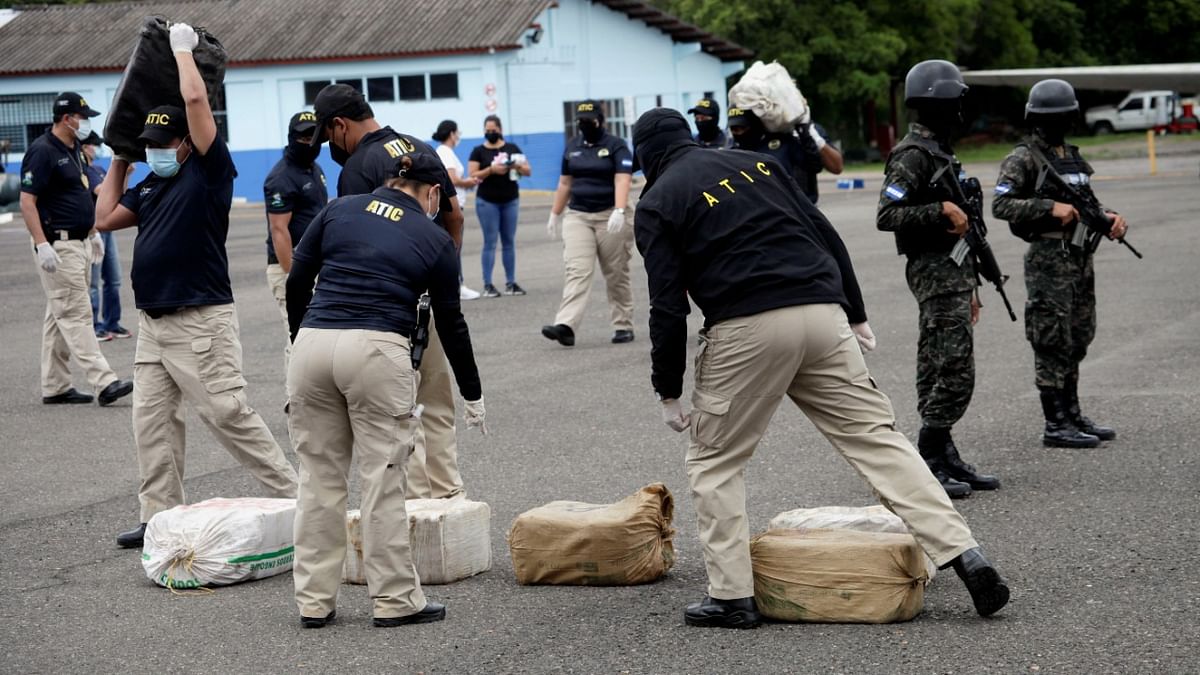 Agents of the Technical Criminal Investigation Agency (ATIC) carry packages containing cocaine seized from an anti-drug operation in Roatan, at Hernan Acosta Mejia Air Base in Tegucigalpa, Honduras. Credit: Reuters photo