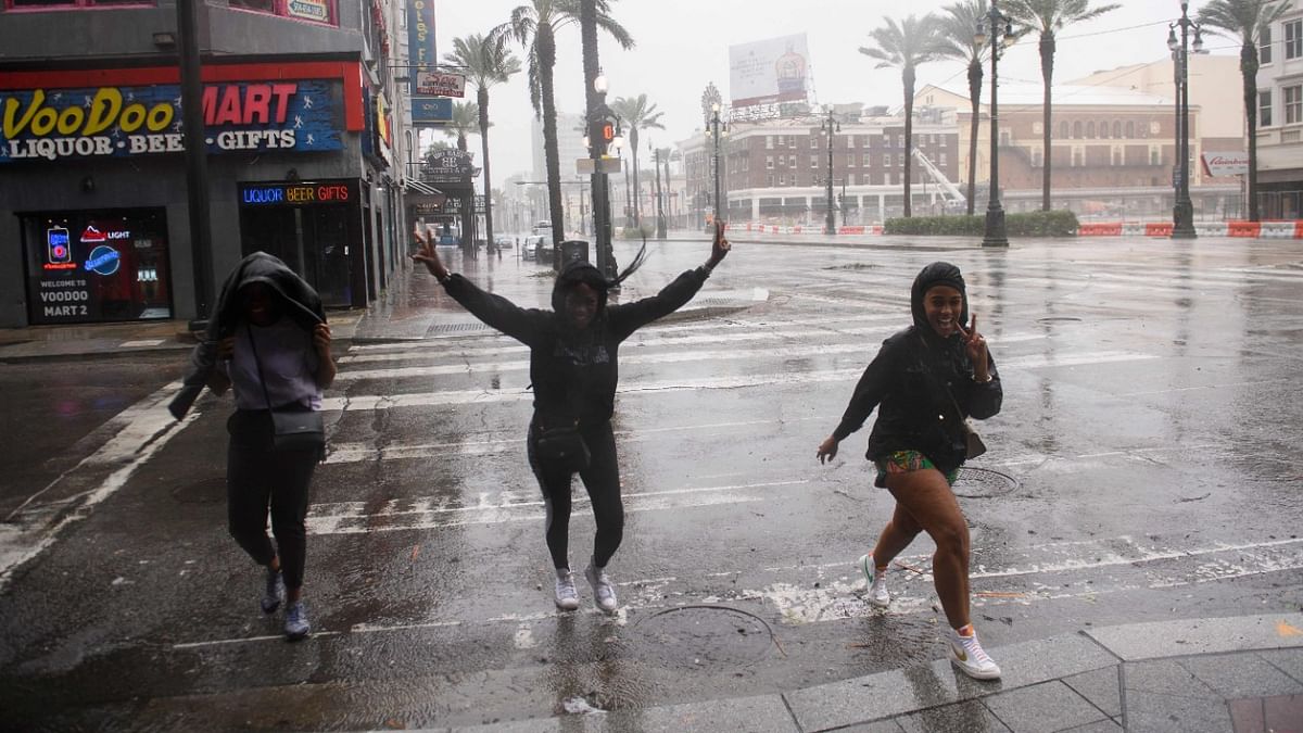 Tourists from New York walk through rain and high winds on Canal Street in New Orleans, Louisiana on August 29, 2021 during Hurricane Ida. Credit: AFP Photo