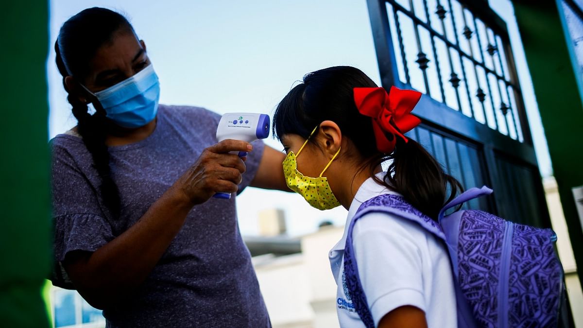 A volunteer checks a student's temperature before entering a school, as in-person classes return after over a year of online lessons as the coronavirus disease (Covid-19) outbreak continues, in Ciudad Juarez, Mexico. Credit: Reuters Photo