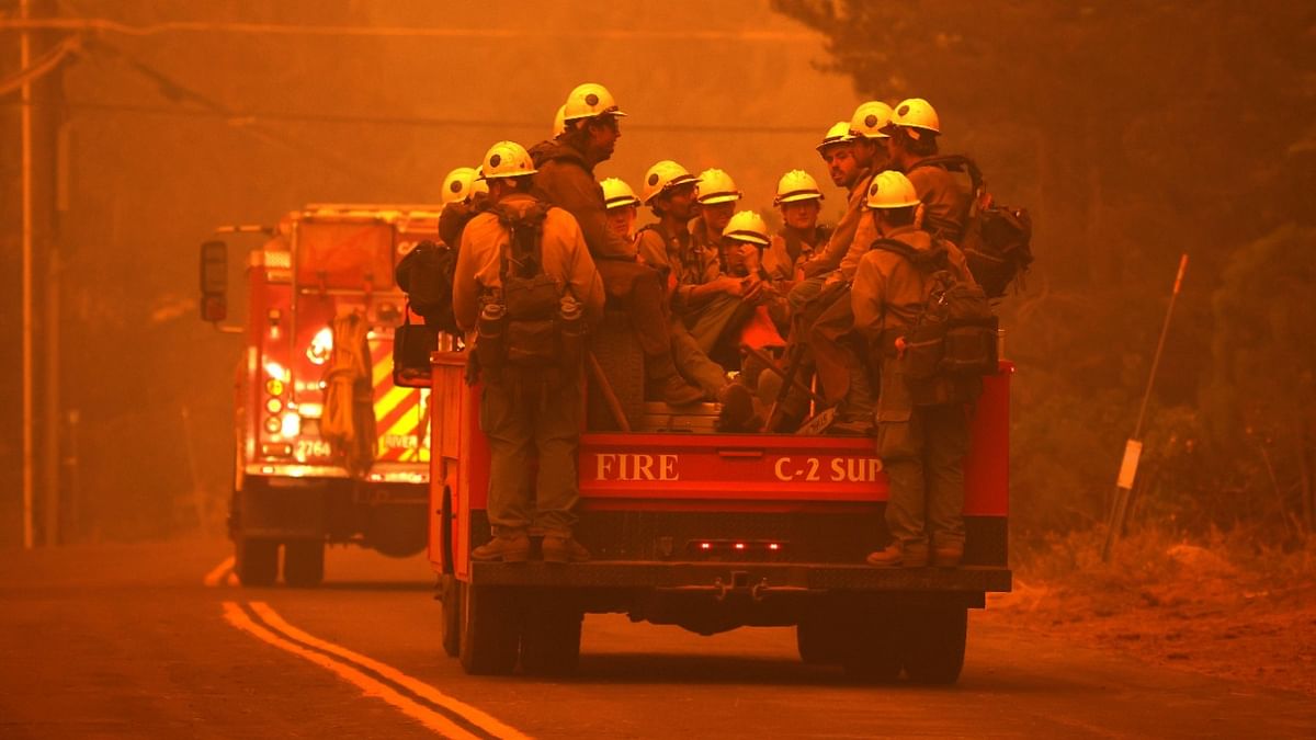 Fire crews ride on the back of a truck as they prepare to battle the Caldor Fire in South Lake Tahoe, California. The fire continues to advance towards South Lake Tahoe and a red flag warning has been issued as high winds begin to kick up. Credit: Justin Sullivan/Getty Images/AFP