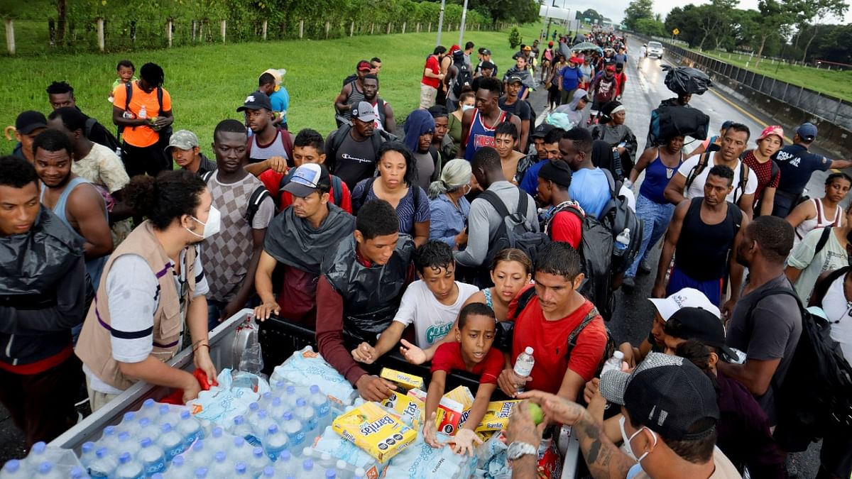 Members of the Fray Matias de Cordova Human Rights Center hand out water and cereal bars to migrants and asylum seekers from Central America and the Caribbean walking in a caravan headed to the Mexican capital to apply for asylum and refugee status, on a highway in Mapastepec, in Chiapas state, Mexico. Credit: Reuters Photo