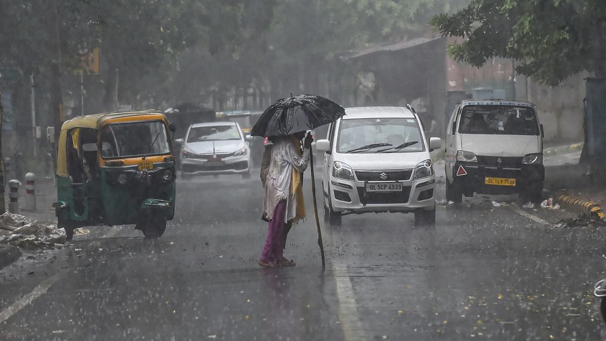 A man with an umbrella crosses the road amid heavy rain in New Delhi. Credit: PTI Photo