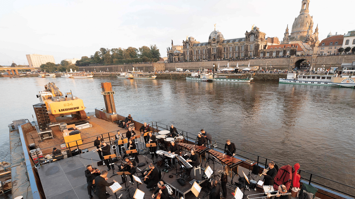 Musicians of the Dresden Symphony Orchestra stand on a boat on the river Elbe as the old town is seen in the background as they play the concert