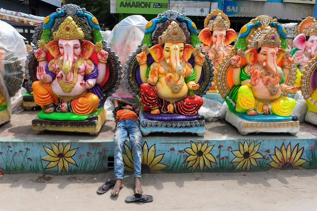 A boy rests between idols of the elephant-headed Hindu God Ganesha displayed for sale at roadside stall ahead of the Ganesh Chaturthi festival in Hyderabad. Credit: AFP Photo