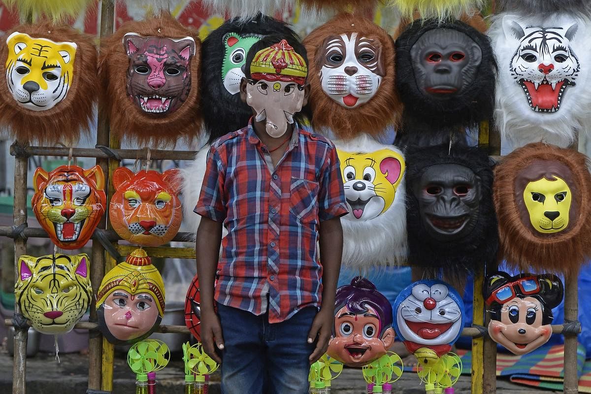 A boy wearing a mask of Ganesha stands in front of a stall to attract customers outside a temple during the Ganesh Chaturthi festival in Hyderabad. Credit: AFP Photo