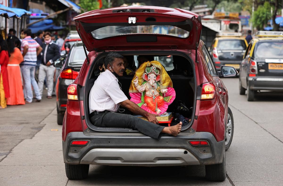 A devotee holds an idol of the Hindu God Ganesh, the deity of prosperity, inside a car, on the eve of the Ganesh Chaturthi festival in Mumbai. Credit: Reuters Photo