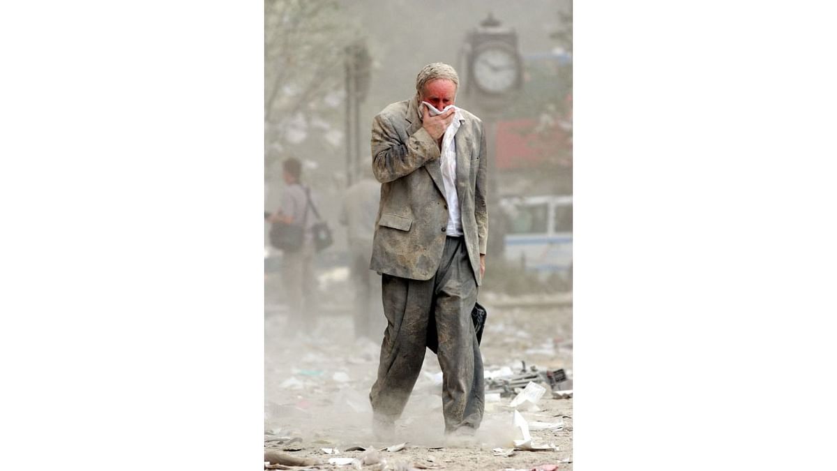 A man covering his mouth walks through dust and debris following the collapse of one of the twin towers of the World Trade Center in New York. Credit: AFP/File Photo