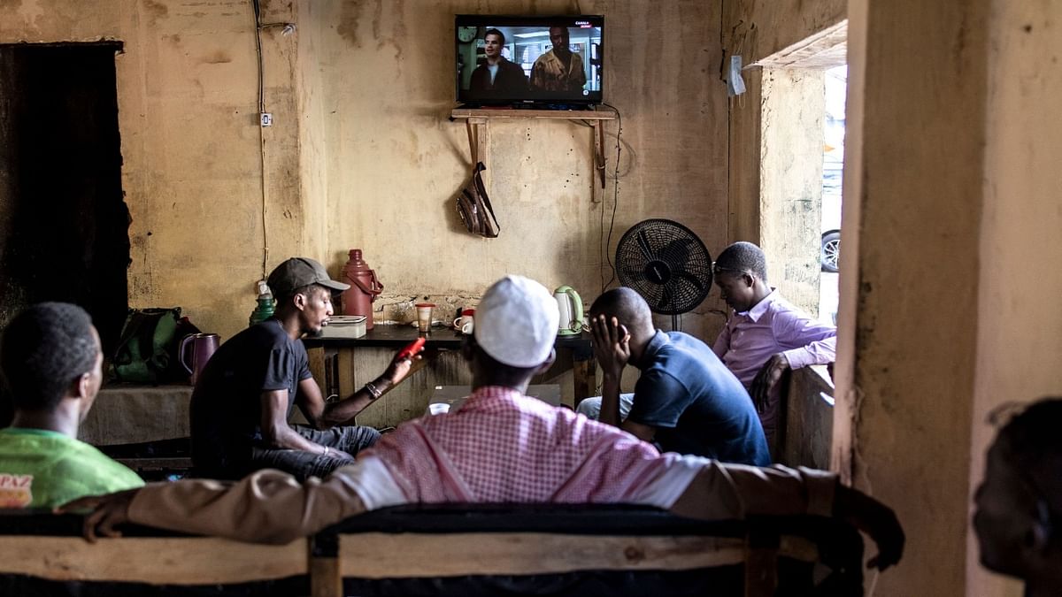 Men sit watching television in Conakry. Credit: AFP Photo