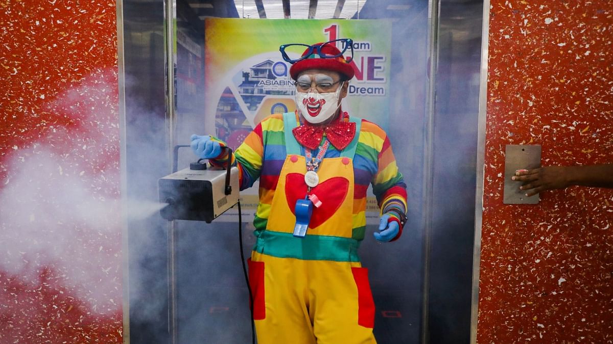 Shaharul Hisam bin Baharuddin, 43, dressed as a clown, disinfects a lift inside a shopping mall in Taiping, Malaysia. Credit: Reuters Photo