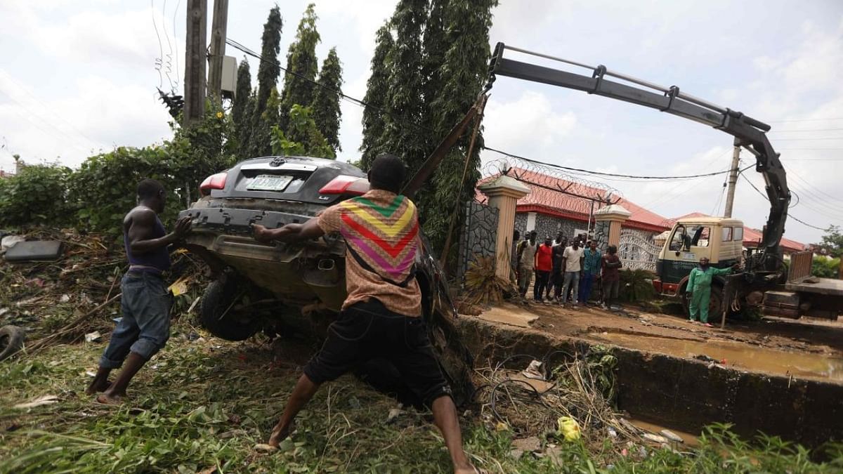 People attempt to pull out a car washed away by flood water on a street affected by floods following a heavy downpour at Trademoore Estate, Lugbe, Abuja, Nigeria. Credit:A FP Photo