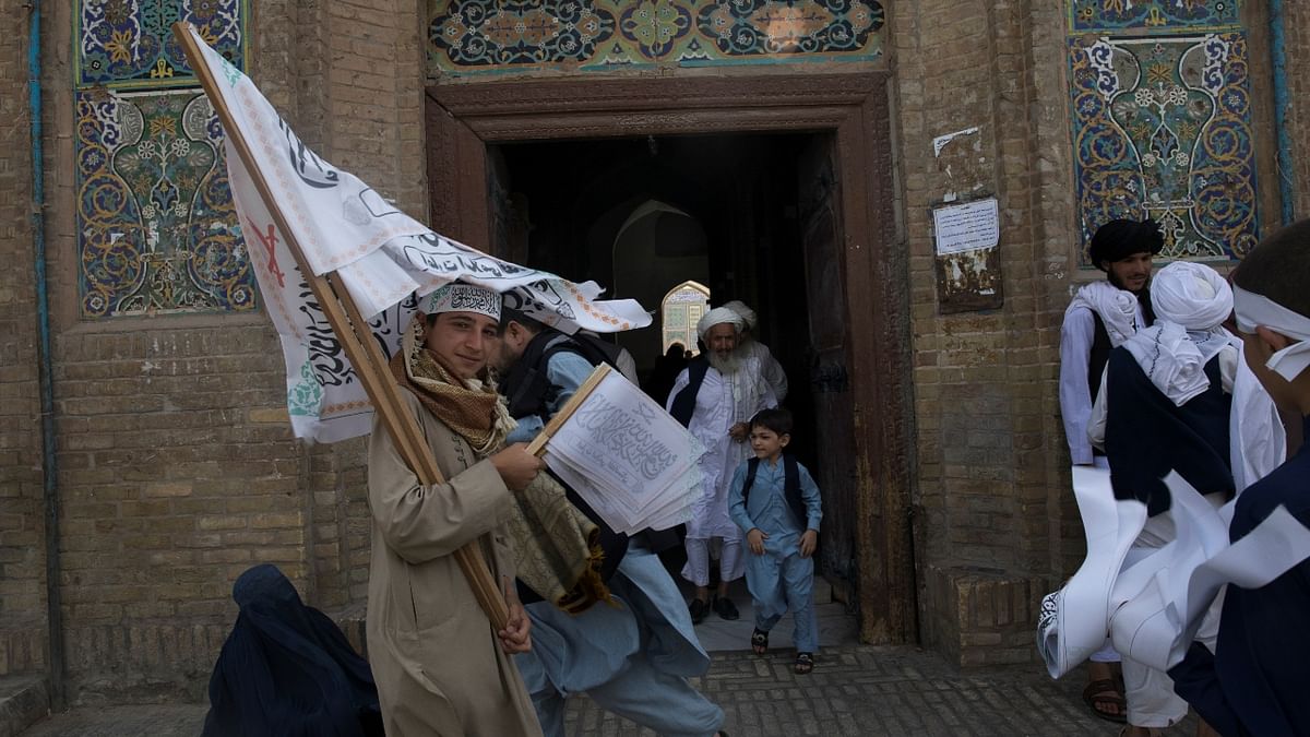 A Taliban supporter carries Taliban flags at a mosque in Herat, Afghanistan. A UN official said 4 million Afghans are facing “a food emergency,” with the majority in rural areas where there is a critical need for funding for planting winter wheat, feed for livestock and cash assistance for vulnerable families, elderly and disabled. Credit: Reuters Photo