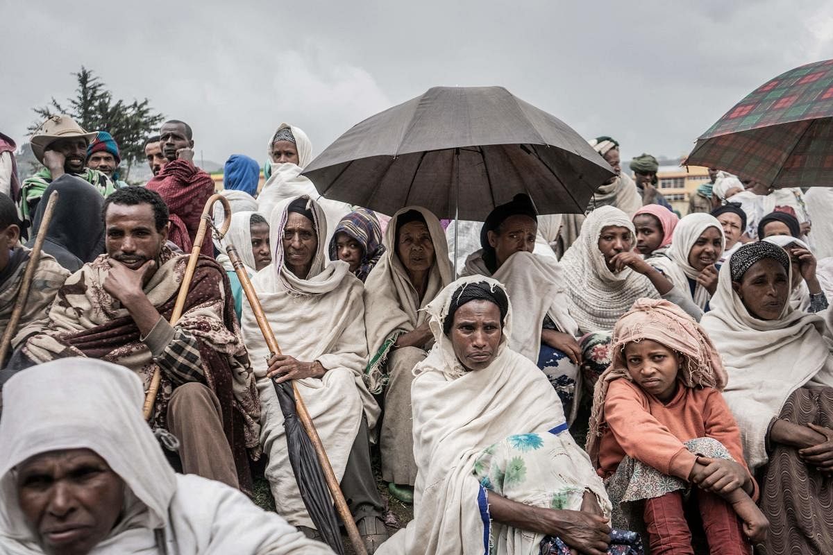 People who fled the war from May Tsemre, Addi Arkay and Zarima gather around in a temporarily built internally displaced people (IDP) camp to receive their first bags of wheat from the World Food Programme (WFP) in Debark, 90 kilometres of the city of Gondar, Ethiopia. Credit: AFP Photo