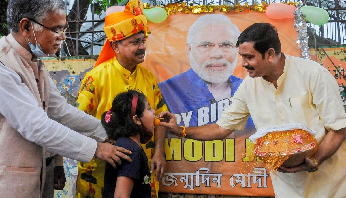 Former BJP West Bengal president Rahul Sinha with party leader Narayan Chatterjee, offers sweets to a child to celebrate Prime Minister Narendra Modi's birthday, at BJP headquarters in Kolkata. Credit: PTI Photo