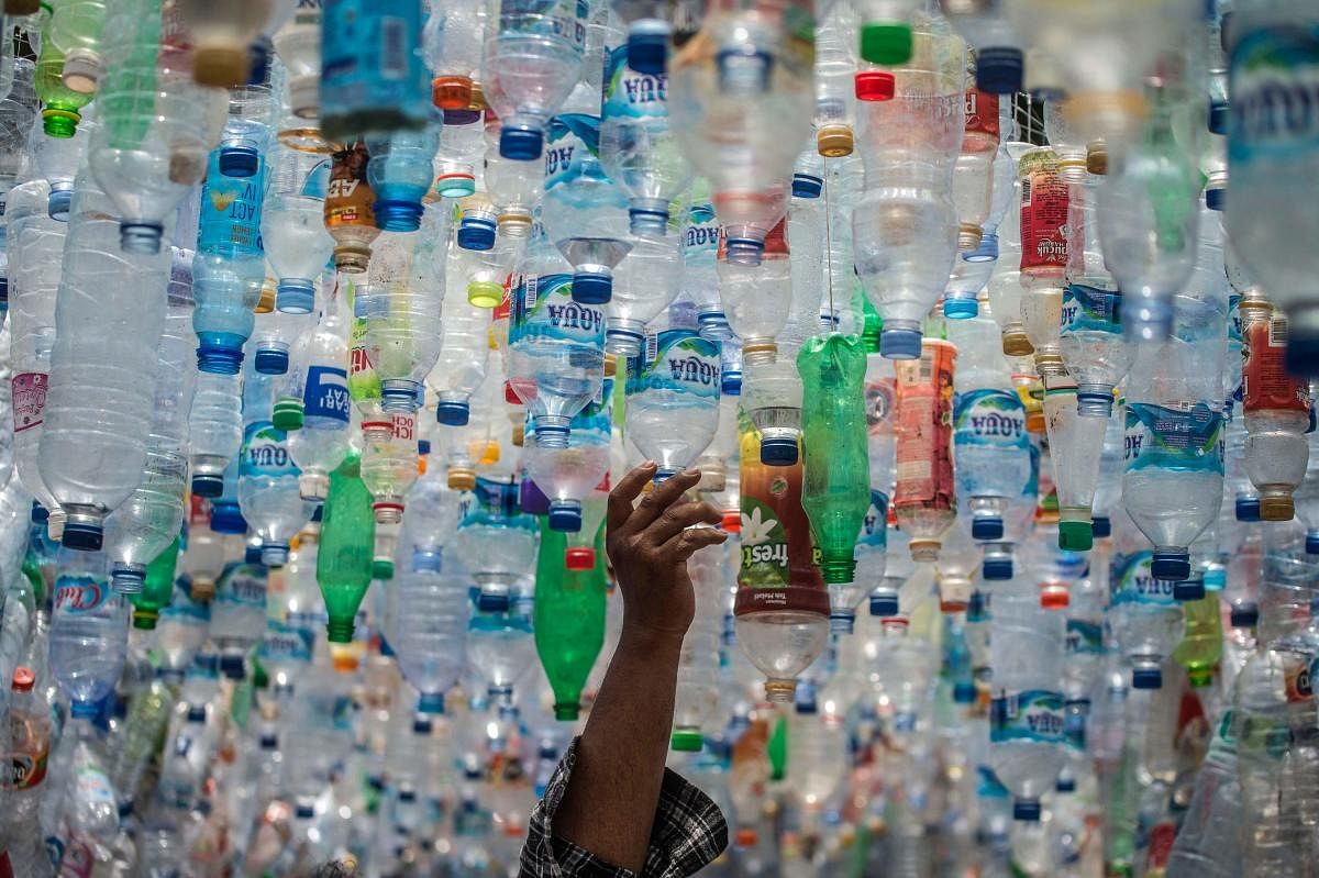 An Indonesian activist from ECOTON (ecological observation and wetland conservation) prepares an installation made with used plastic, including 4,444 bottles, collected from the river in Gresik to raise public awareness of plastic waste in rivers and oceans. Credit: AFP Photo