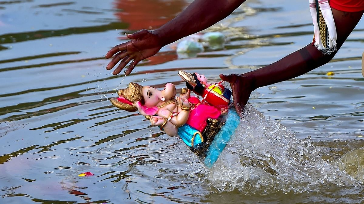 A volunteer immerses an idol of Lord Ganesh in a makeshift pond at Ulsoor lake following Ganesh Chaturthi festival, in Bengaluru. Credit: PTI Photo