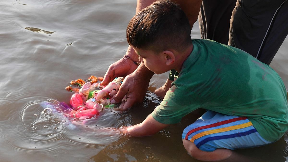 A young devotee immerses an idol of Ganesha on a river on the outskirts of Amritsar. Credit: AFP Photo