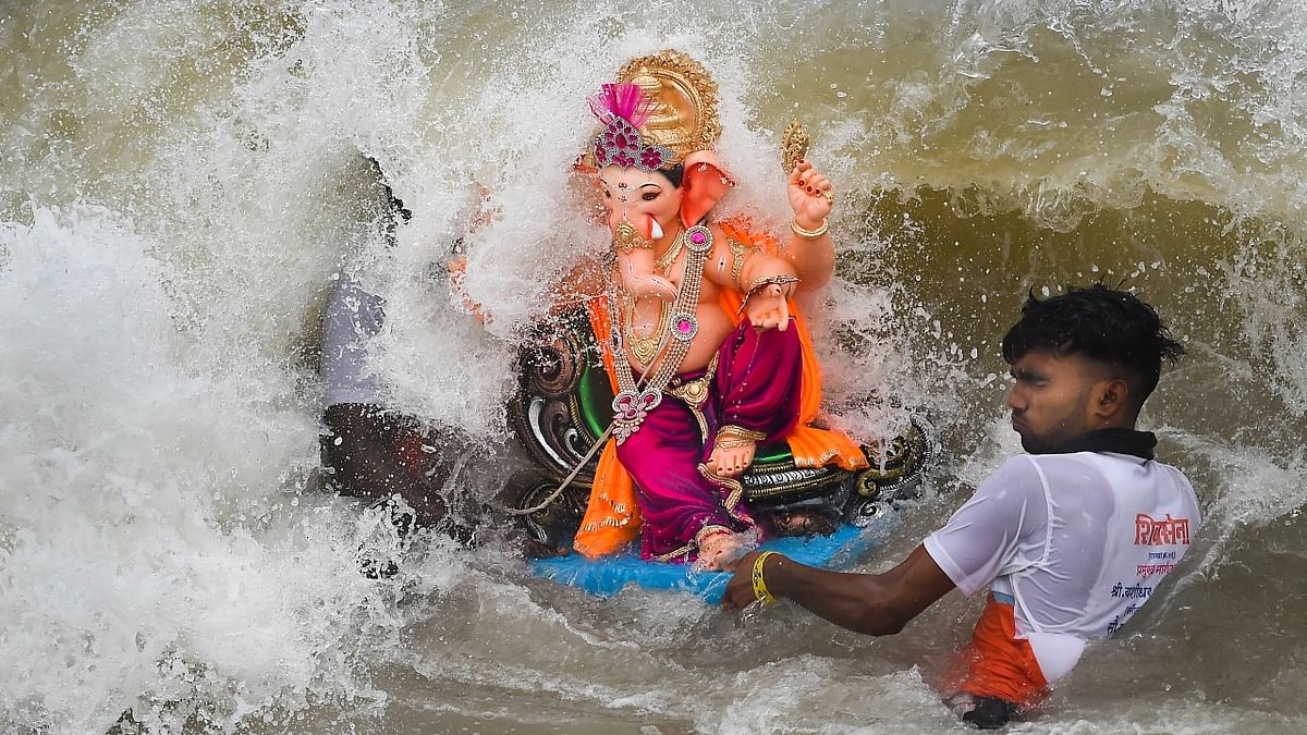 A volunteer immerses an idol of Lord Ganesha in the Arabian Sea on the 5th day during the Ganesh festival in Mumbai. Credit: PTI Photo