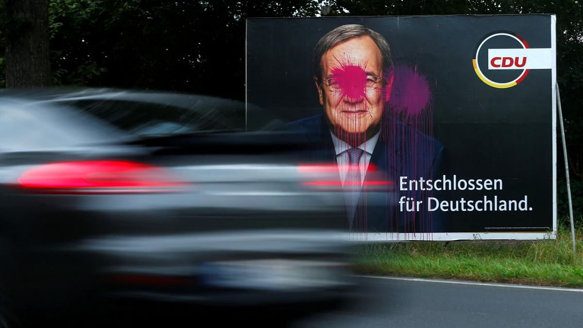 Paint is splattered on a placard of Armin Laschet, candidate for Chancellor of Germany's Christian Democratic Union party CDU for the September 26 German general elections, as a car drives by in Cologne, Germany. Credit: Reuters photo