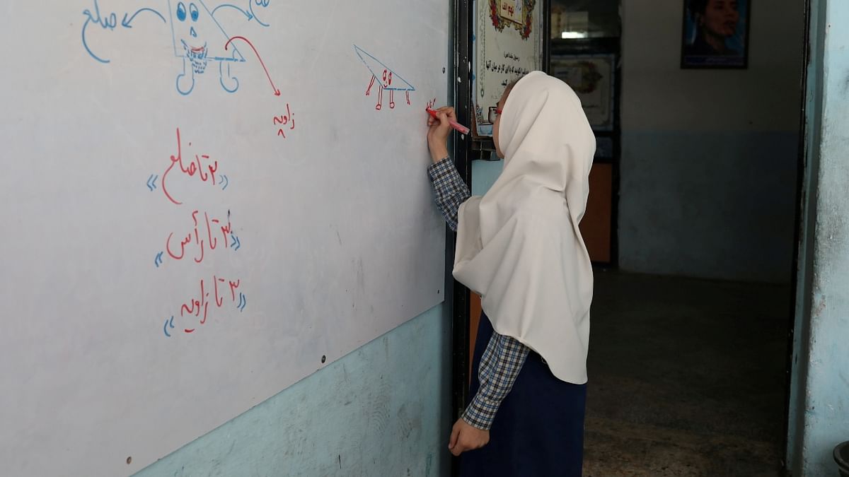 An Afghan girl is seen writing on a whiteboard in the classroom at a school in Kabul. Credit: WANA (West Asia News Agency) via Reuters Photo