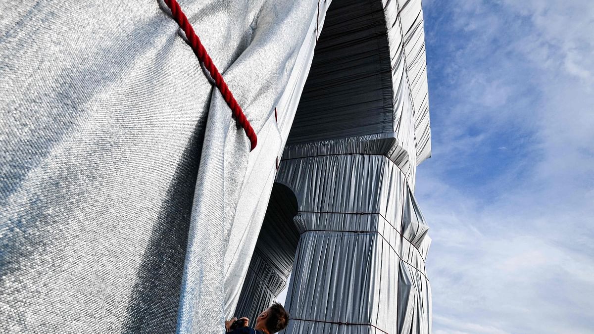 a little over a year after Christo’s death at the age of 84, “L’Arc de Triomphe, Wrapped” is a reality. About 270,000 square feet of silvery blue fabric, shimmering in the changing light of Paris, hugs the monument commissioned by Napoleon in 1806 at the giddy height of his power. The polypropylene material, its tone reminiscent of the city’s distinctive zinc roofs, is secured but not held rigidly fast by almost 1.9 miles of red rope, in line with the artist’s meticulous instructions. Credit: AFP Photo