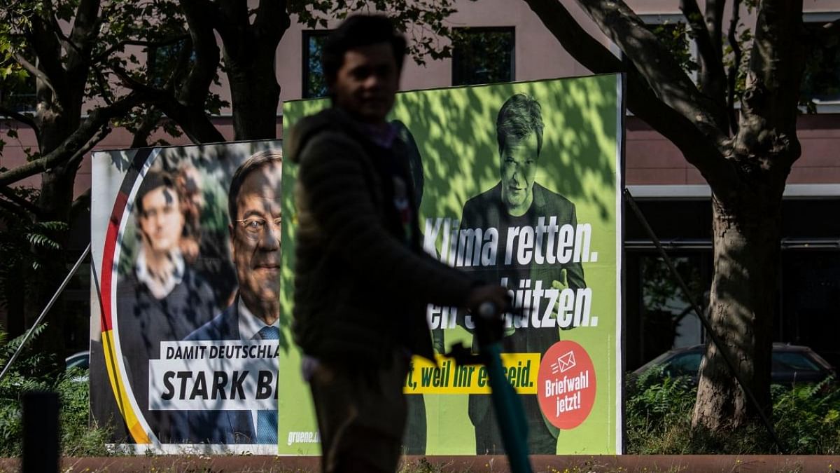A youth on a scooter passes election campaign posters for Christian Democratic Union (CDU) party leader and candidate for Chancellor Armin Laschet (L) and the Green Party (Die Gruenen) featuring co-leader of Germany's the Greens Robert Habeck in Berlin on September 2, 2021, ahead of parliamentary elections on September 26. Credit: AFP Photo